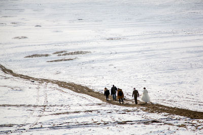 Rear view of people walking on snow covered land