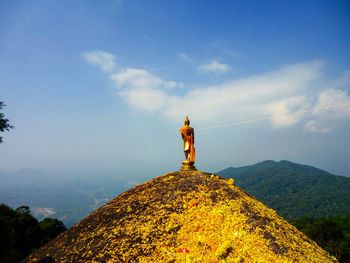 Buddha status on mountain against sky