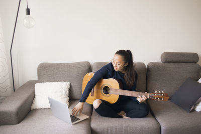 Woman holding guitar on sofa