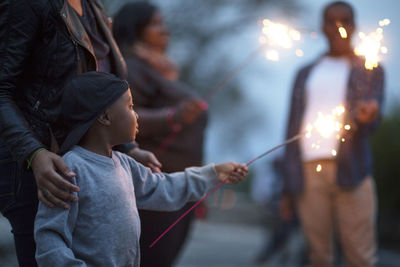 Boy holding sparkler at dusk