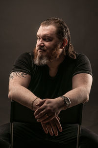 Man looking away while sitting against black background