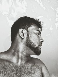 Close-up of shirtless man looking away against wall