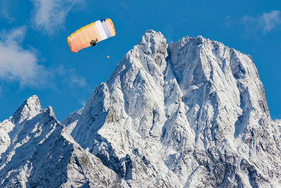 Low angle view of kite flying over snowcapped mountains against sky