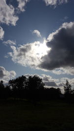 Silhouette trees on field against sky