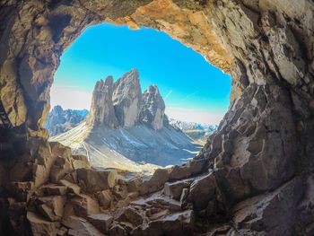 Rock formations seen through cave against sky