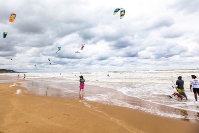 People enjoying at beach against sky