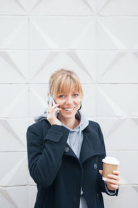 Smiling man holding coffee cup on floor