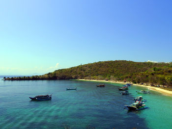 Boats in sea against clear blue sky