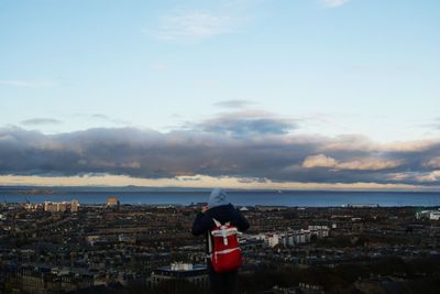 Rear view of woman standing by sea against sky