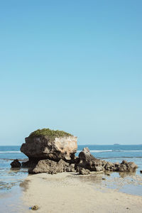 Rock formation on beach against clear blue sky