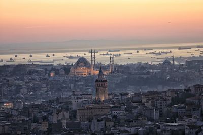 Cityscape and sea against sky during sunset