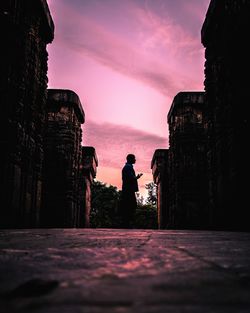 Surface level shot of man standing against sky during sunset