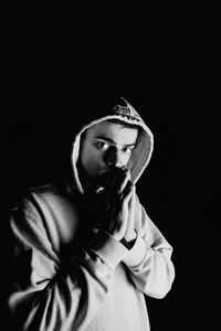 Portrait of young man looking away against black background