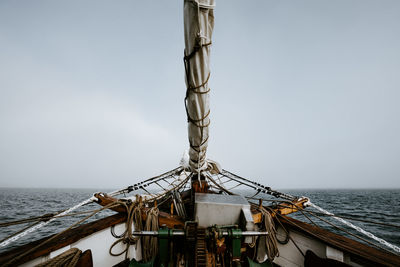 Sailing ship moving on sea by mountains against sky