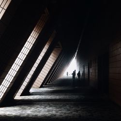 Silhouette people walking in illuminated corridor