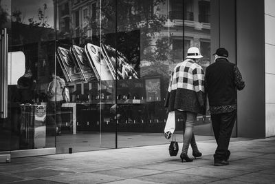 Rear view of people walking on street in city