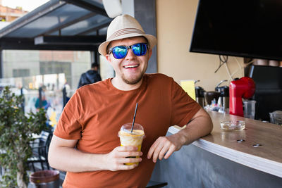 Portrait of young man standing against drink