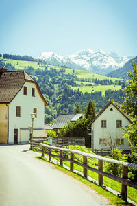 Houses and trees by mountains against sky