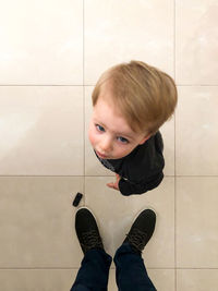 Portrait of boy standing on tiled floor at home