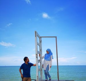 Couple standing at beach against sky