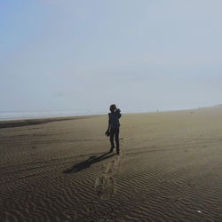 Full length of man standing on beach against sky