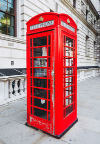 Red telephone booth on sidewalk in city