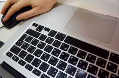 Cropped image of hand working on laptop in office
