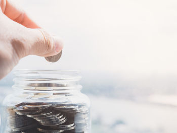 Close-up of hand holding jar against white background