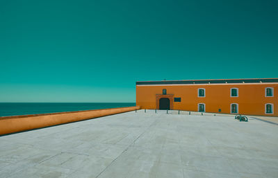 Empty esplanade with an orange building and sea in the background