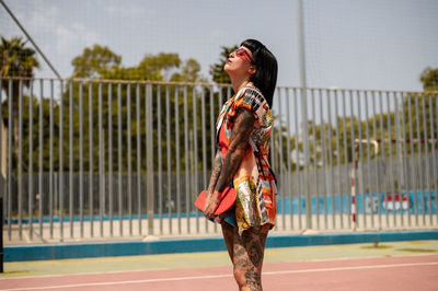 Caucasian girl with tattoos and short black hair on a sports ground with a skateboard in her hands