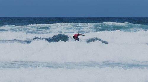 Man surfing on sea against clear sky