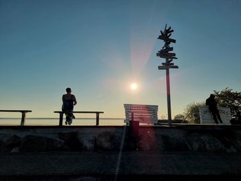 Low angle view of man standing on retaining wall against clear sky