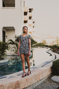 Portrait of young woman standing by swimming pool