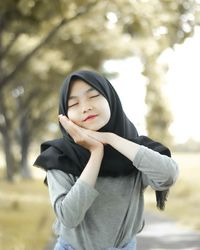 Portrait of beautiful woman standing against trees