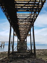 Low angle view of pier over sea against sky