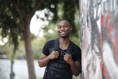 Portrait of smiling man standing by wall