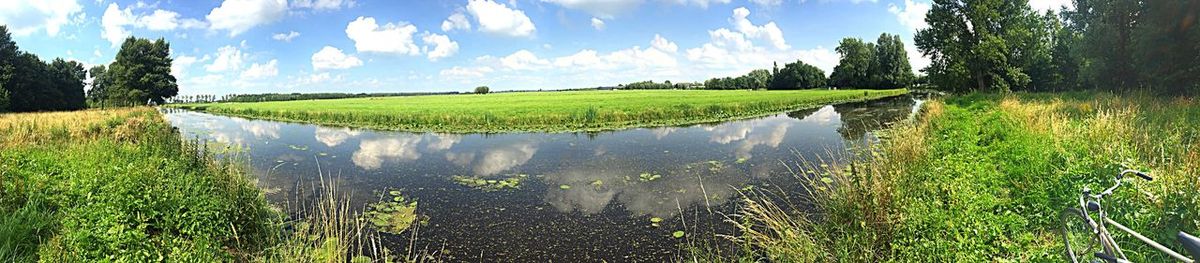 Panoramic view of lake by field against sky