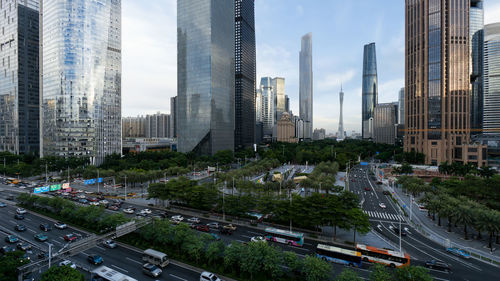 Traffic on road by buildings against sky in city