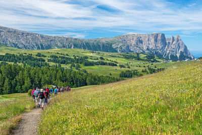 People walking on mountain road against sky