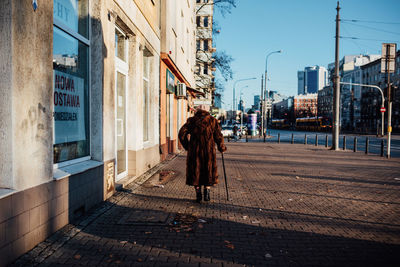 Rear view of woman walking on street amidst buildings