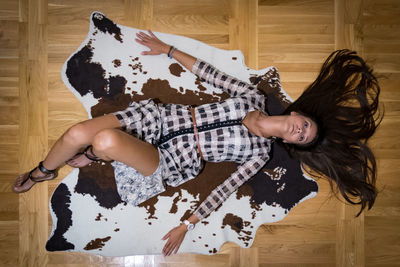 High angle view of woman lying on hardwood floor at home