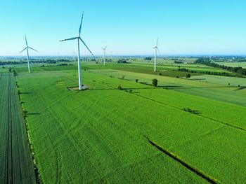 Windmills on field against sky