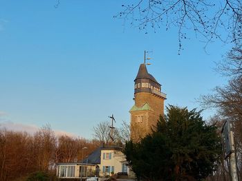 Tower amidst trees and buildings against clear blue sky