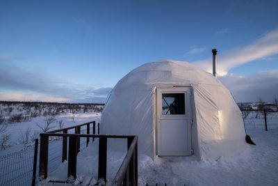 Built structure on snow covered land against sky