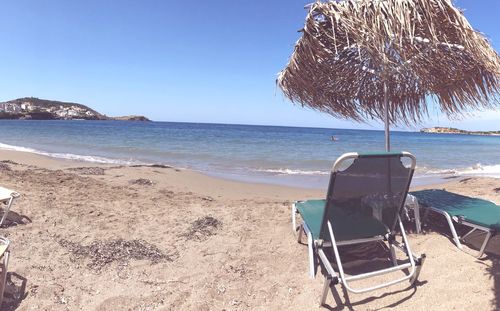 Chairs on beach against clear blue sky