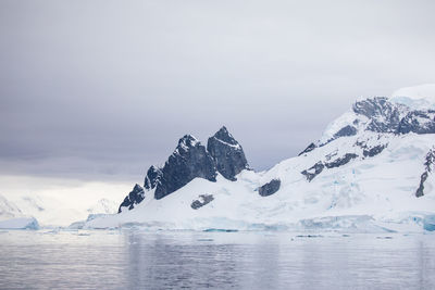 Scenic view of sea and snowcapped mountain against sky