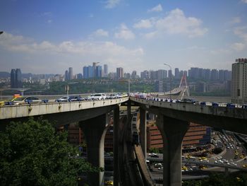 Bridge over river amidst buildings in city against sky