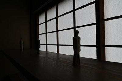 Silhouette people standing by window