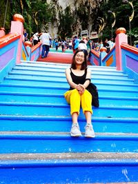 Full length portrait of young woman sitting on steps 