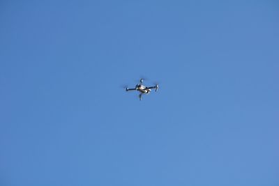 Low angle view of drone flying against clear blue sky